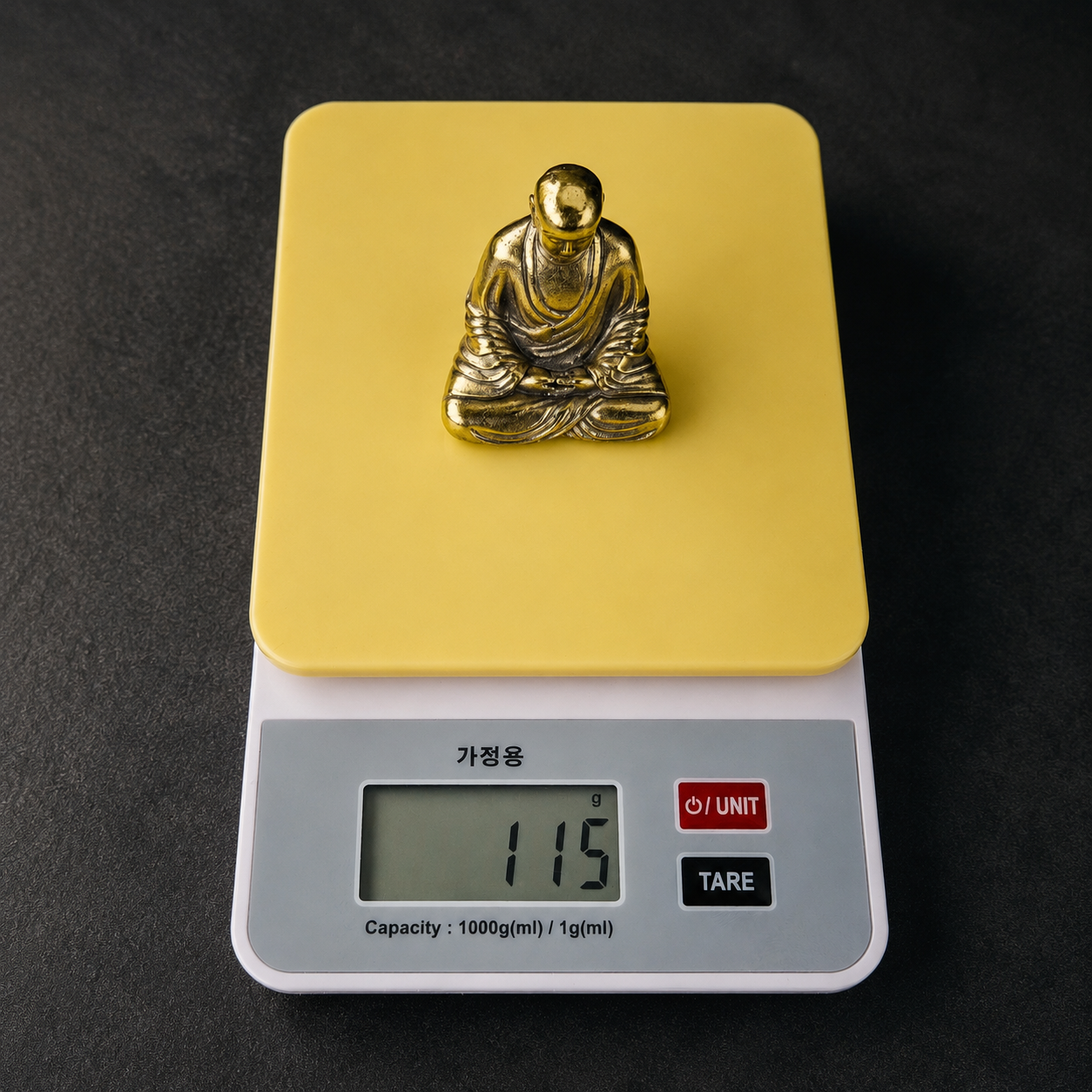 지장보살상 지장보살상을 전자저울에 올려 약 115g 무게를 확인하는 모습 이미지